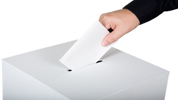 A hand with ballot and ballot box